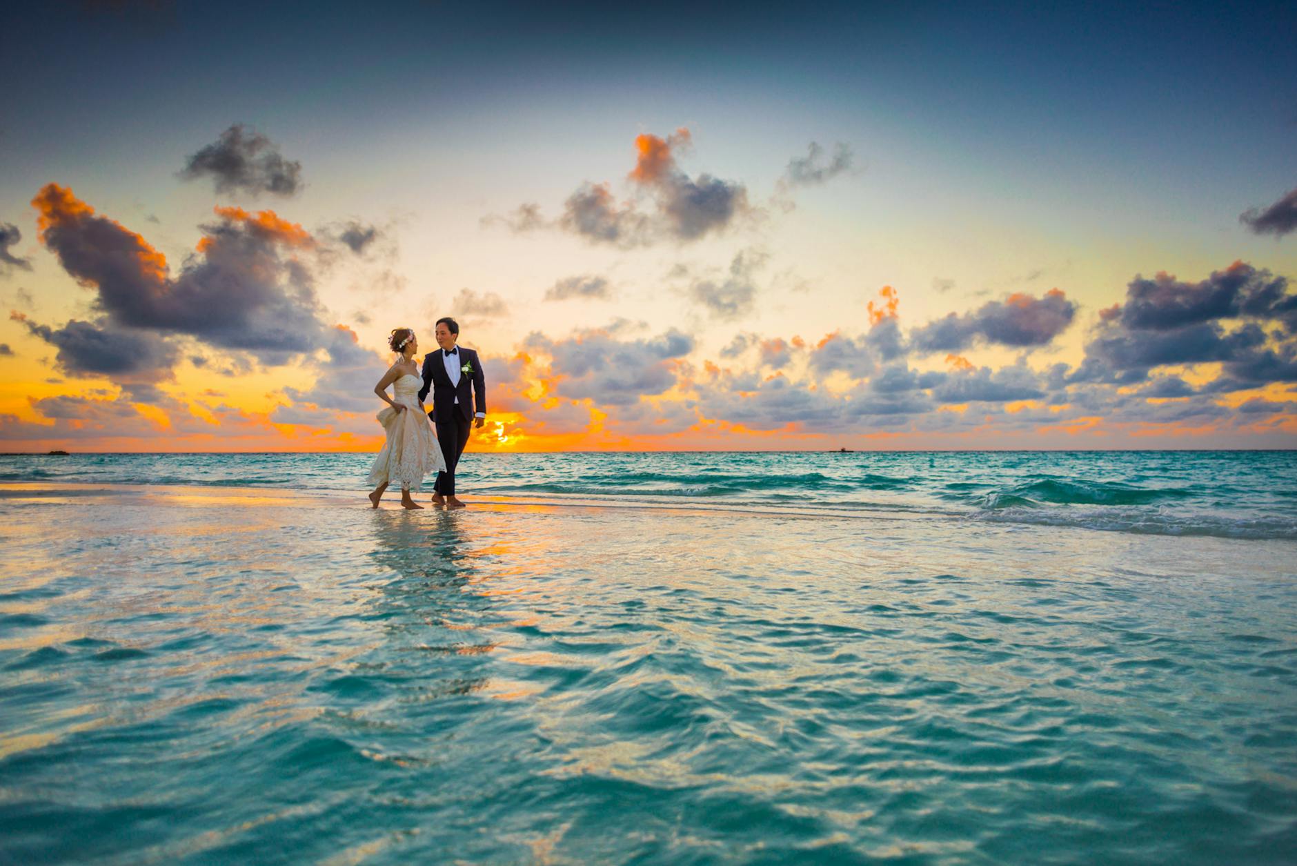 man and woman walking of body of water